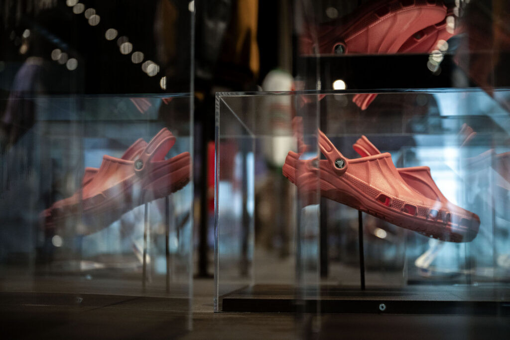 A pair of orange crocs sits in a glass display case at History Colorado.