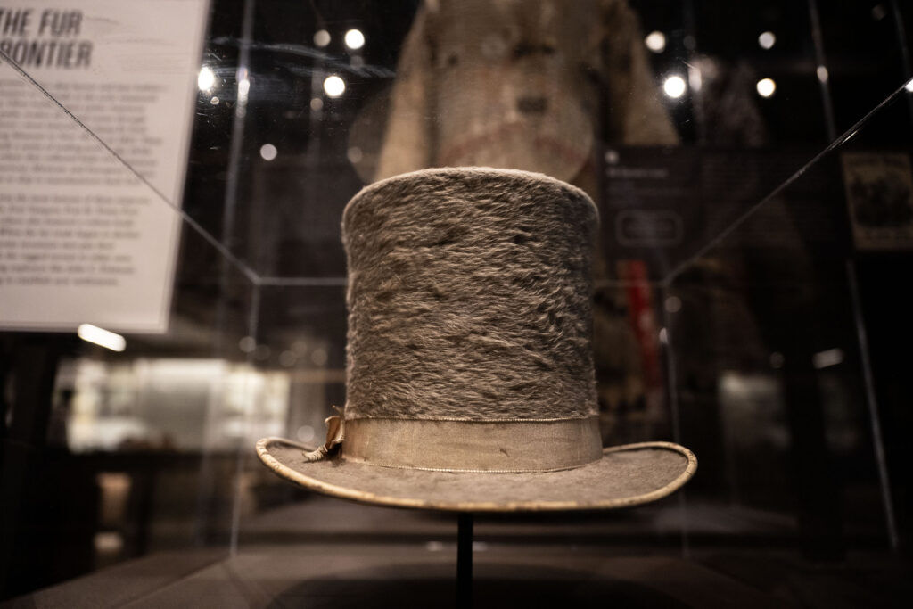 A beaver felt top hat on display behind a glass case at History Colorado