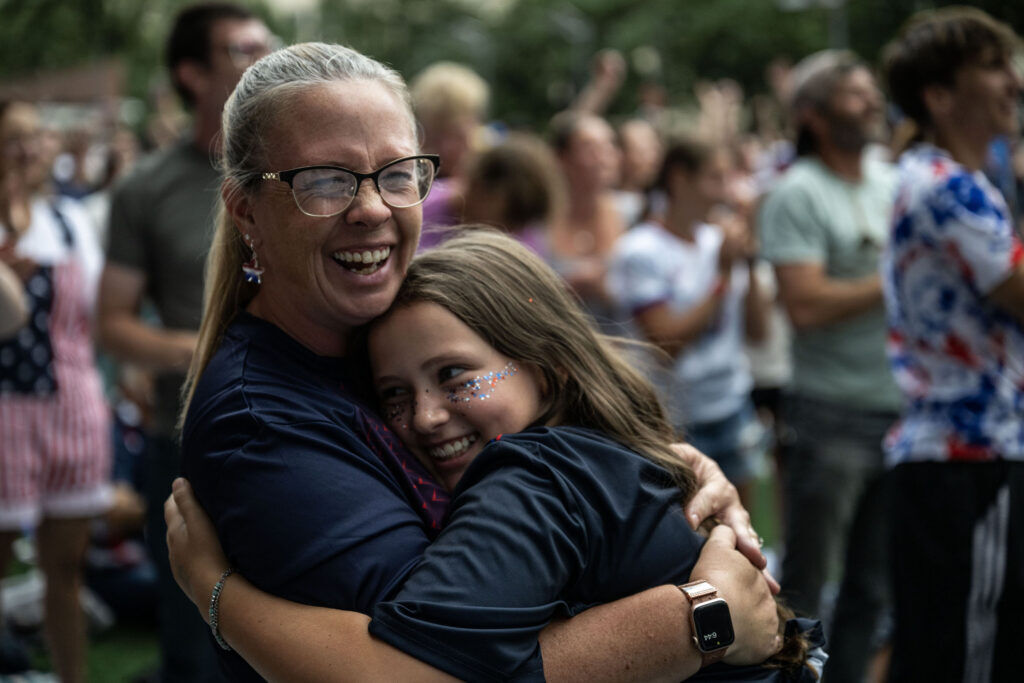 Jill Jones hugs her daughter, Harper, 10, as they celebrate a USA goal during a watch party for the USA vs Bosnia-Herzegovina game at Skyline Park on Wednesday, July 1, 2026.