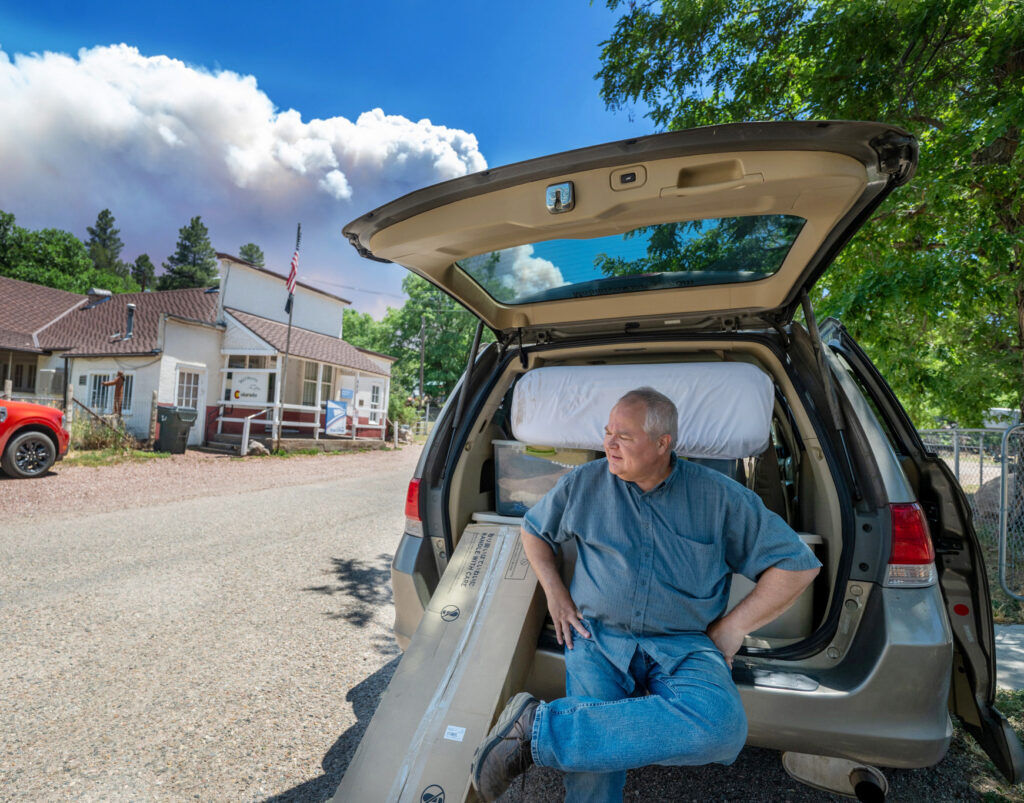 Pastor Andy Smart takes a break after loading up his car as smoke looms over the tiny town of Wetmore on Wednesday, July 1, 2026. The town was under pre-evacuation notice on Wednesday morning as the Aspen Acres Fire heads north towards Wetmore. (The Gazette, Jerilee Bennett)