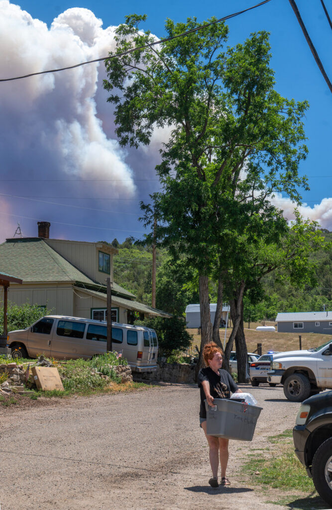 Shelby Garrett carries some of her belongings to her car as smoke looms over the tiny town of Wetmore on Wednesday, June 1, 2026. The town was under pre-evacuation notice on Wednesday morning as the Aspen Acres Fire headed towards them. (The Gazette, Jerilee Bennett)