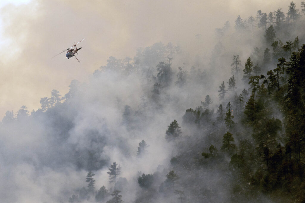 A helicopter drops a bucket of water on the Aspen Acres Fire near Colorado City on Friday, July 3, 2026.