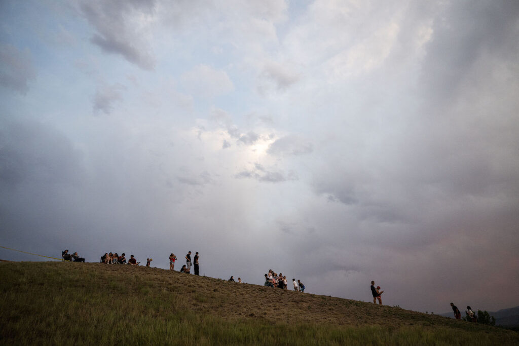 People watch the sunset from a hill at Clement Park as they wait for the start during a fireworks show as part of the park’s annual Red, White and You celebration on Friday, July 3, 2026.