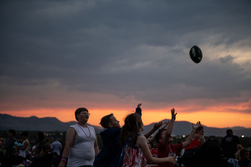 Kids play catch with a football at sunset at Clement Park’s annual Red White and You event on Friday, July 3, 2026. The event ended in a fireworks show.