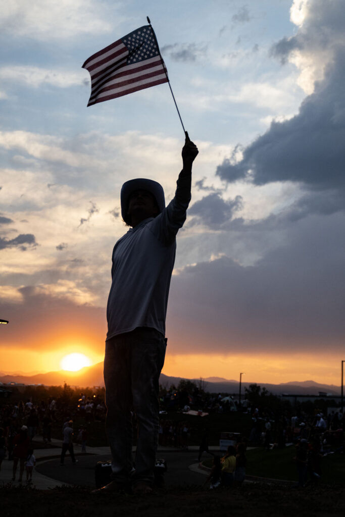 A man waves the flag at sunset in Clement Park during the Red White and You celebration on Friday, July 3, 2026.