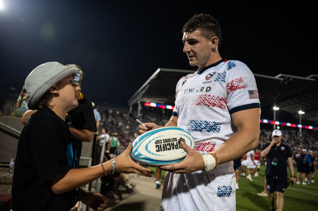 USA number 8 Paddy Ryan signs a ball for a fan at the end of the USA vs Portugal game at the Rugby World Nations Cup at Dicks Sporting Goods Park on Saturday, July 4, 2026. USA won the match 30-29. USA won the match 30-29.