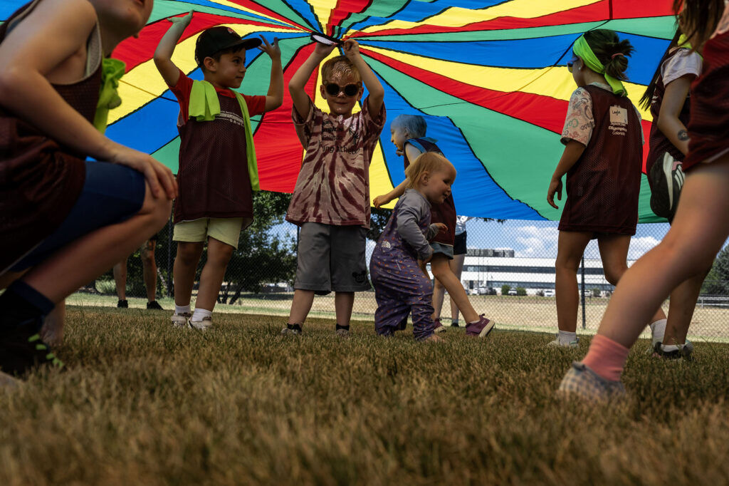 Kids duck under a rainbow tarp during a Youth Sports Day clinic for special olympics young athletes on Friday, July 10, 2026. Athletes learned basketball, street hockey, soccer, lacrosse, and dance during the event.