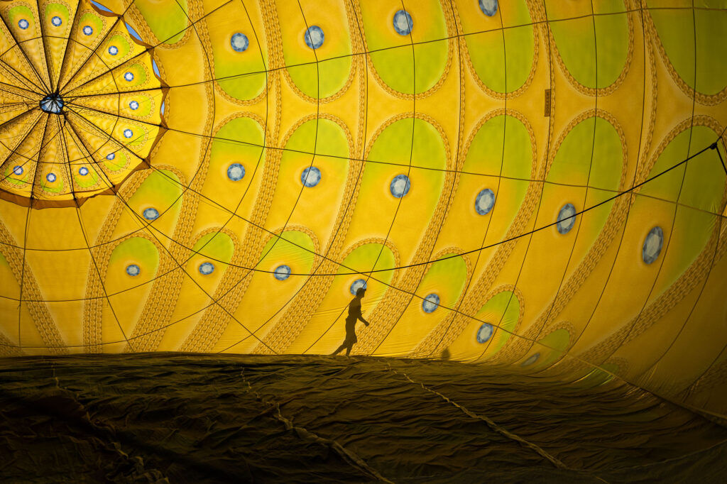 A shadow is reflected on the side of a hot air balloon in the early morning light as crews work to inflate their balloons during the Erie Balloon Festival on Saturday, July 11, 2026.