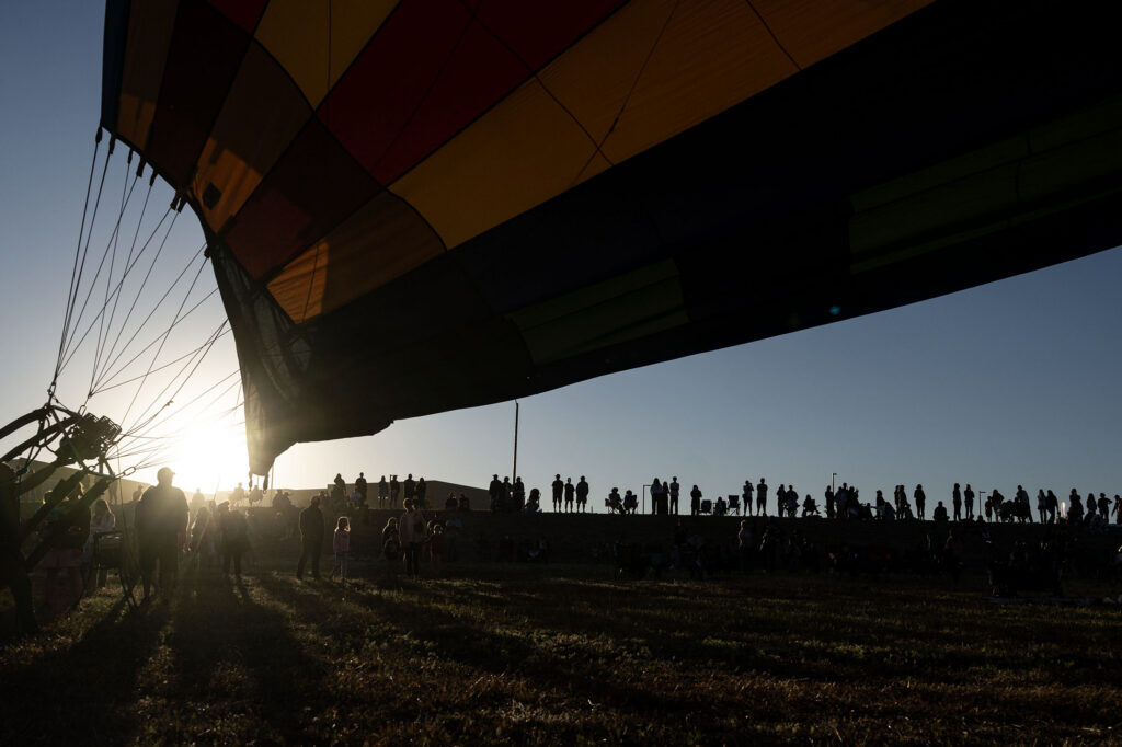 A crowd watches from the road as balloons prepare for liftoff in a field near Erie high school during the Erie Balloon Festival on Saturday, July 11, 2026.