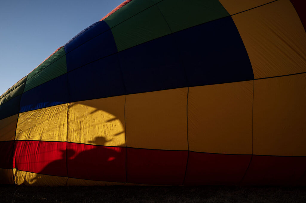 A shadow is reflected on the side of a hot air balloon in the early morning light as crews work to inflate their balloons during the Erie Balloon Festival on Saturday, July 11, 2026.