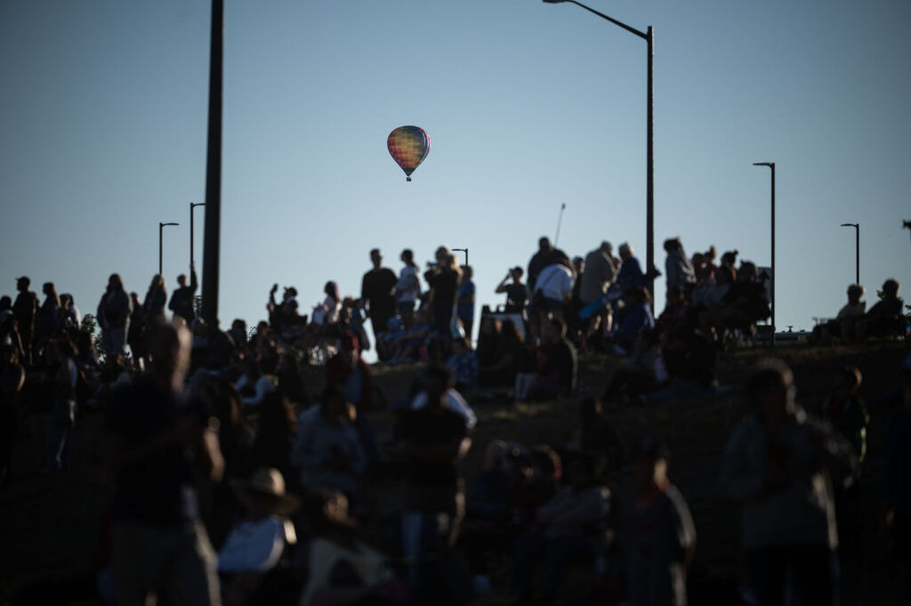 A hot air balloon floats past the crowd as they watch the mass ascension from a field near Erie High School during the Erie Balloon Festival on Saturday, July 11, 2026.