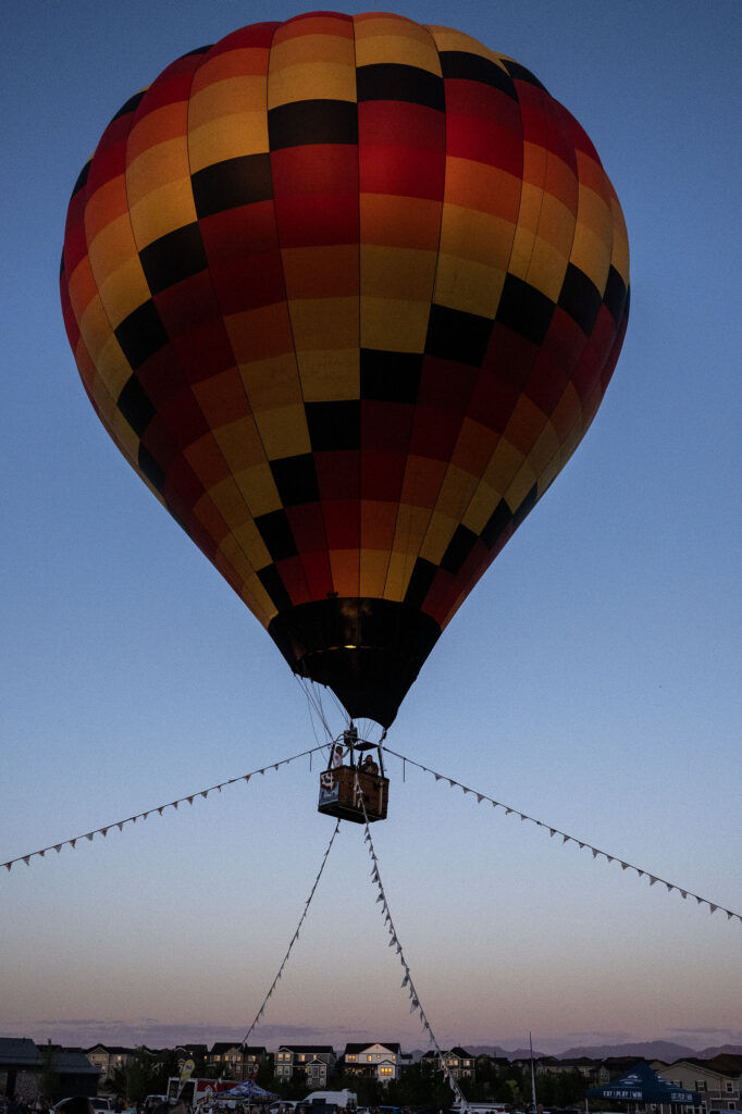 A tethered balloon takes guests up to watch as other hot air balloons prepare for liftoff during the Erie Balloon Festival on Saturday, July 11, 2026.