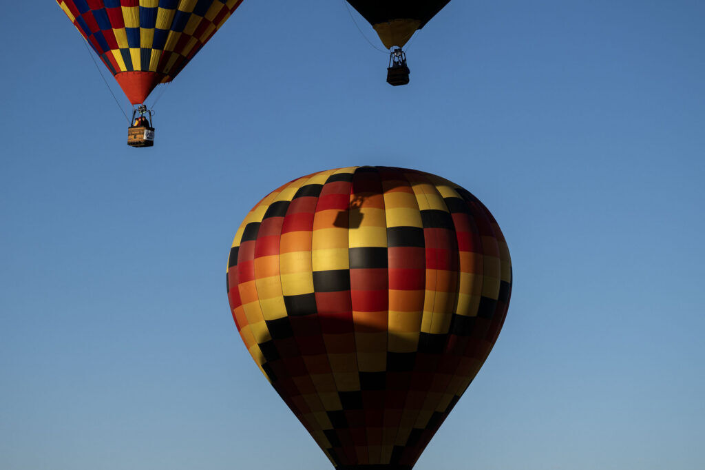 Two balloons float by a tethered hot air balloon during the Erie Balloon Festival on Saturday, July 11, 2026.
