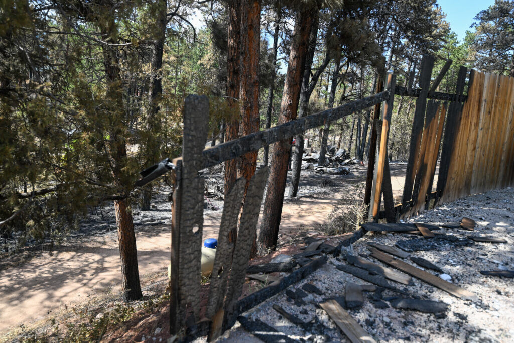 Looking through a charred fence at a burned home along a devastated street near Pine Dr. in Beulah after the Aspen Acres Fire on Tuesday, July 14, 2026. (The Gazette/ Jerilee Bennett)