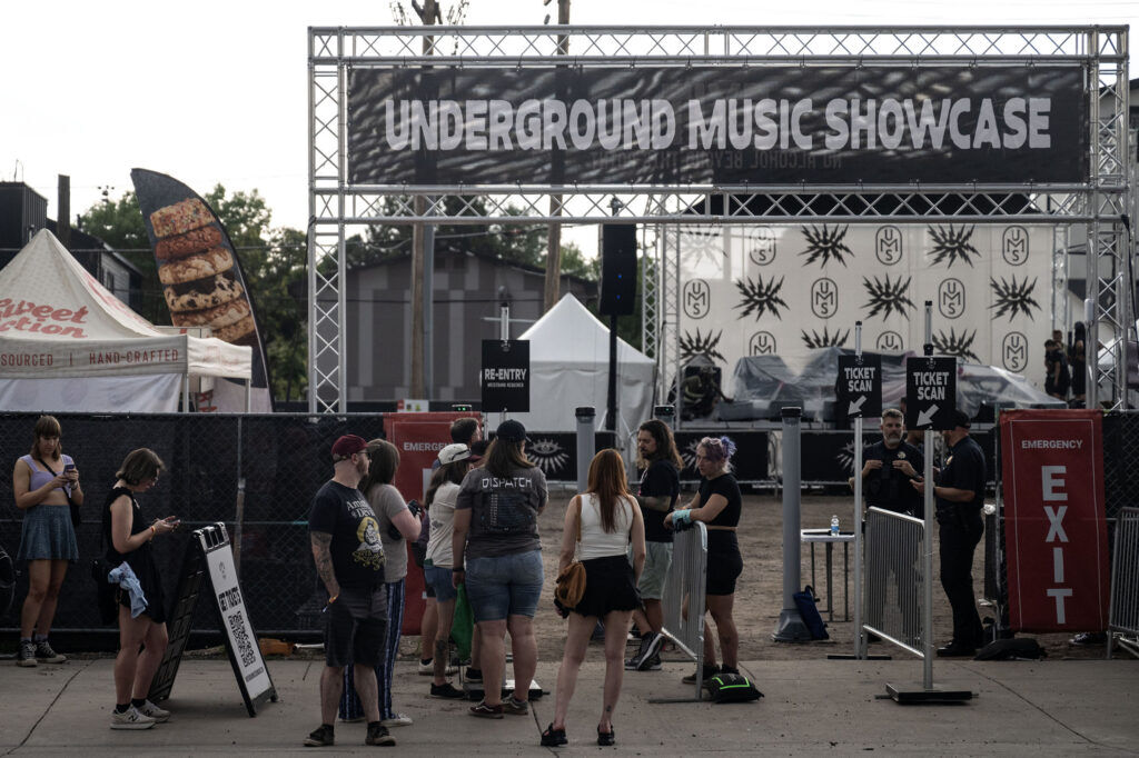 People wait for news after the two main stages were postponed due to weather on the first night of the Underground Music Showcase in RiNo on Friday, July 24, 2026.