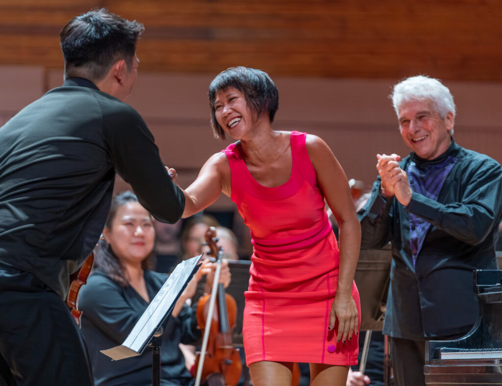 Yuja Wang is seen smiling and shaking hands with members of the Colorado Music Festival Orchestra