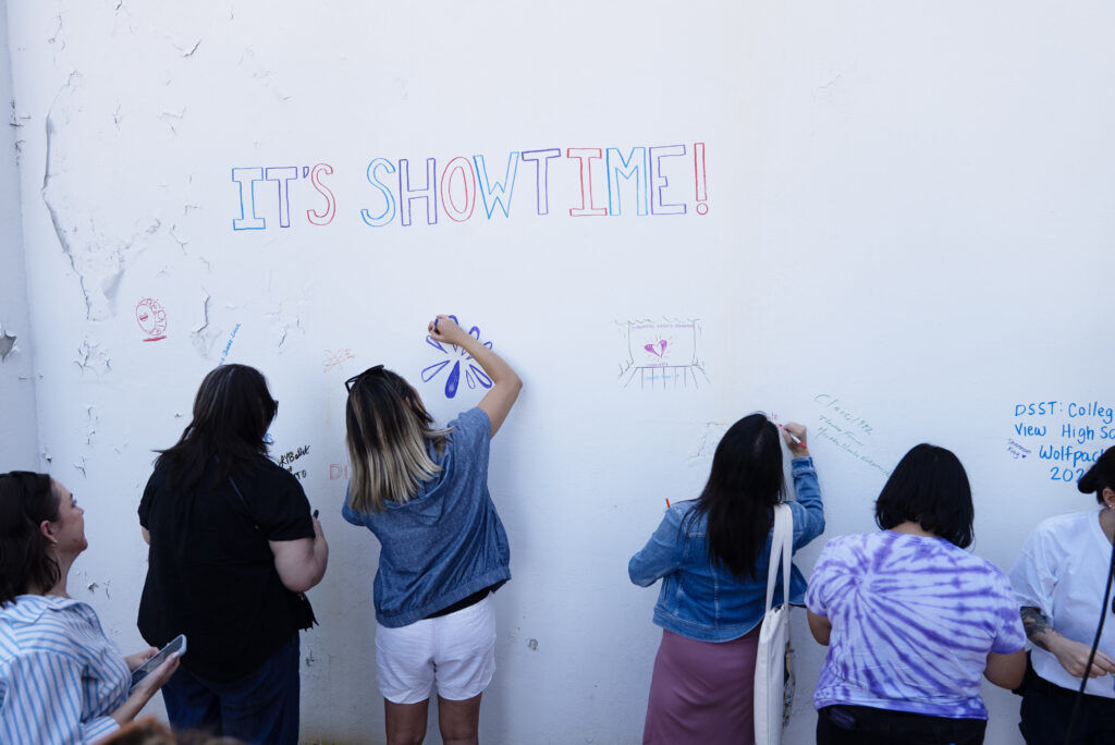 teenagers can be seen drawing well wishes for Loretto Theatre rennovation