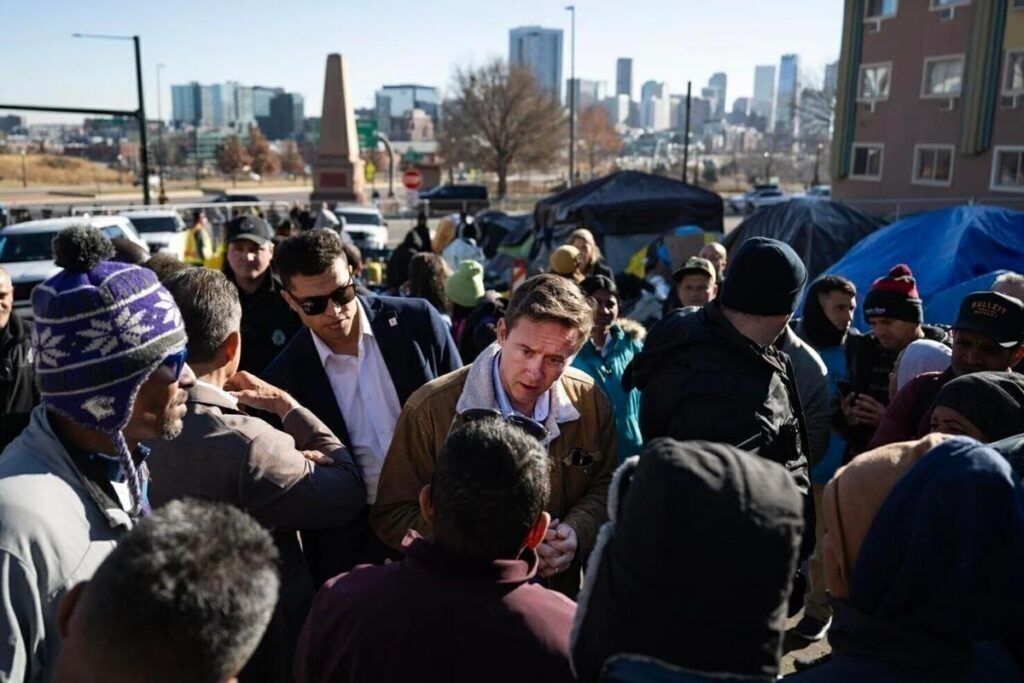 Denver Mayor Mike Johnston is pictured talking with immigrants at a Denver makeshift camp.