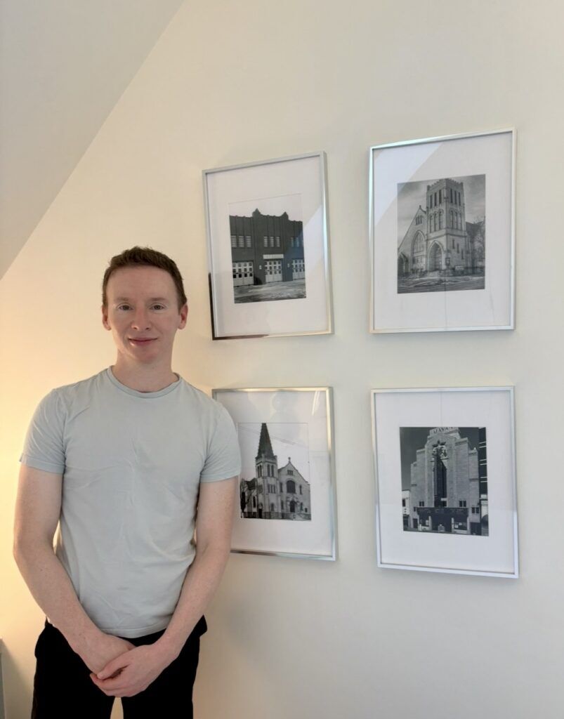 Kevin Henderson stands in front of pictures of historic houses from Denver