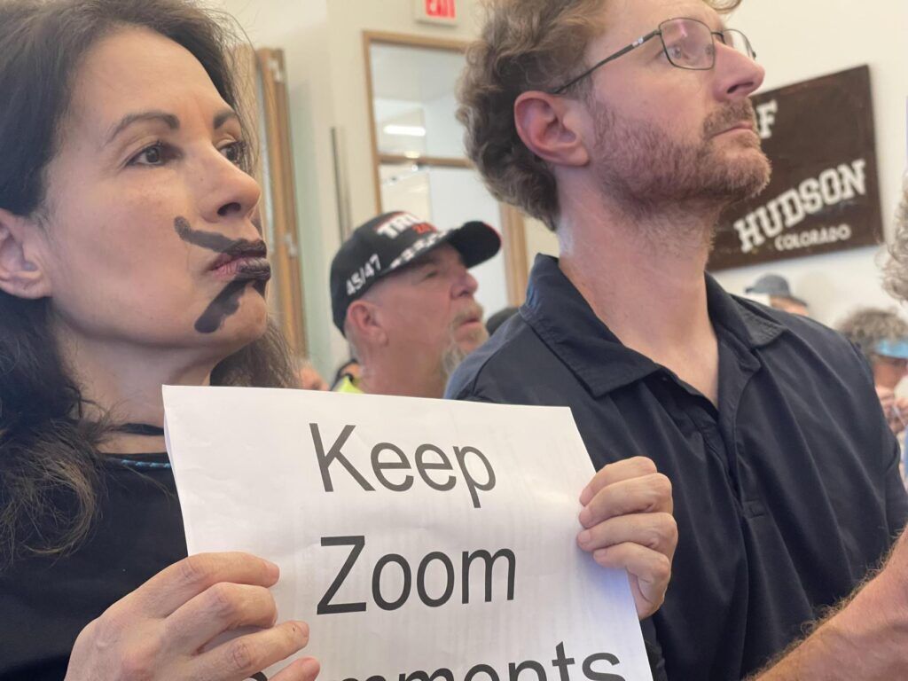 Two people stand holding a sign
